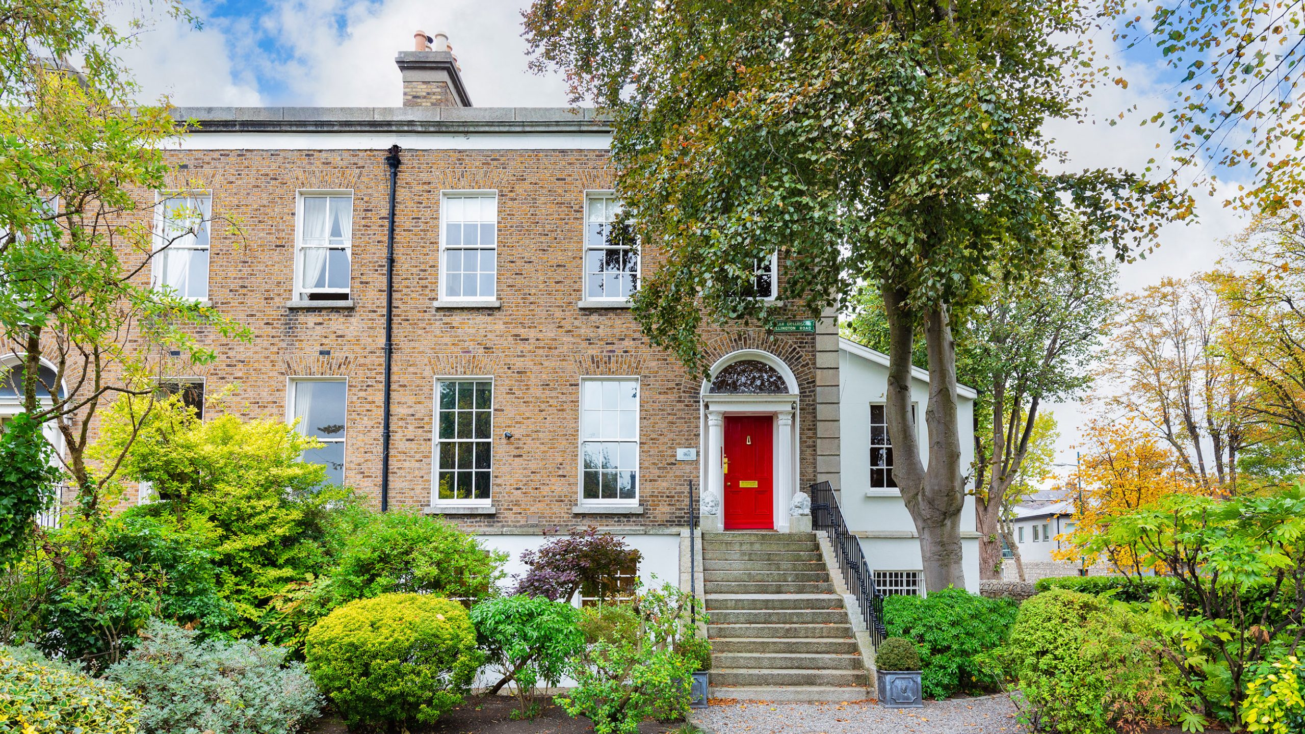 Expert Removals A brick house with a red door and bushes.